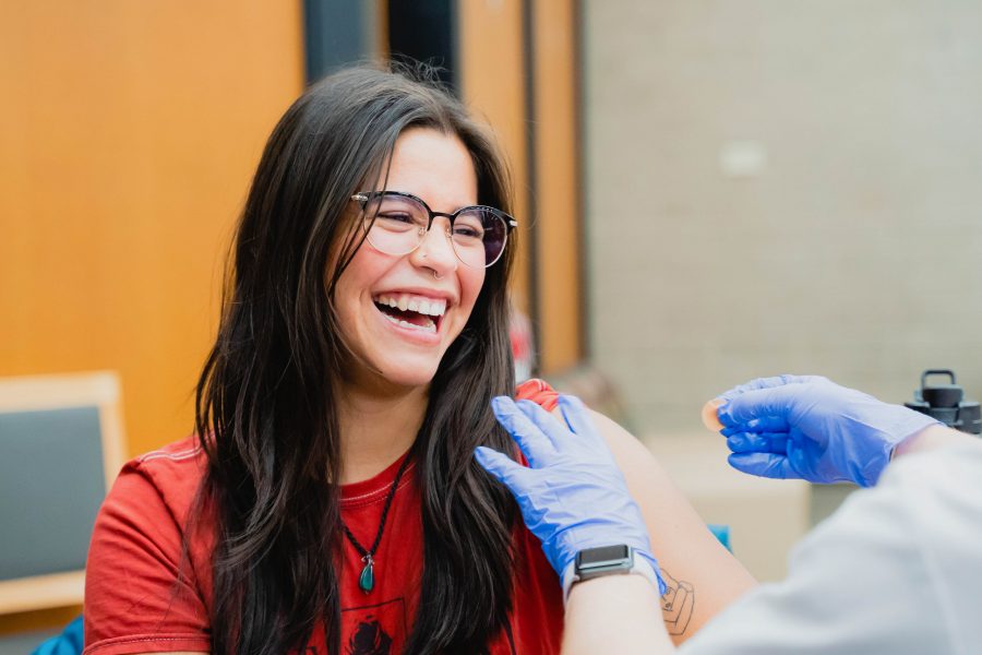 young woman laughing while receiving a shot in the arm