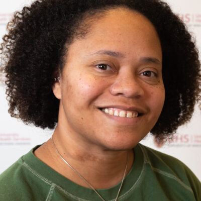 Josie Montanez-Tyler has medium-length curly dark brown hair and is wearing a green shirt.