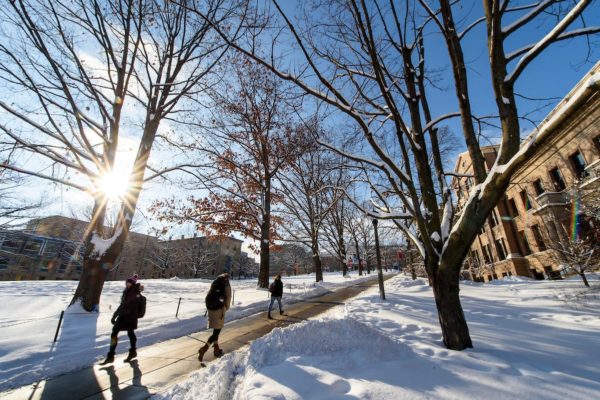 Students walk along the sidewalks leading to and from Bascom Hill on a snowy day.