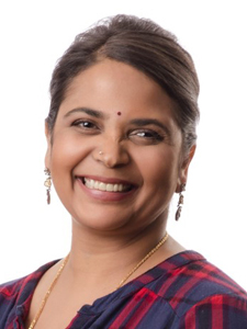 Dr. Josyula is pictured wearing earrings and smiling