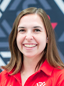 Eliza Barter has shoulder-length brown hair and wears a red shirt.