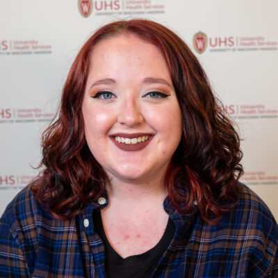 Heather has red hair and is pictured in a plaid shirt.
