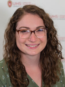 Gina Williamson is a woman with long brown hair, glasses, and is wearing a green shirt.