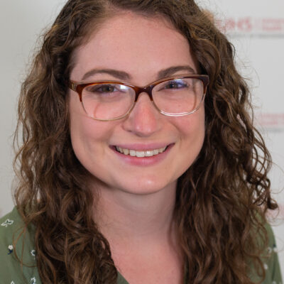 Gina Williamson is a woman with long brown hair, glasses, and is wearing a green shirt.