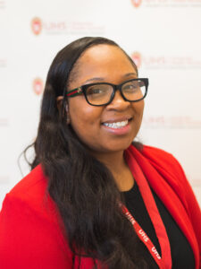 A woman wearing glasses and a red sweater with long brown hair.