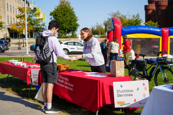 A student speaking with a UHS staff member at the Mental Wellbeing Resource Fair outside