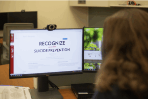 A person with long brown hair looks at a computer screen displaying the Recognize, Respond, Refer online suicide prevention training