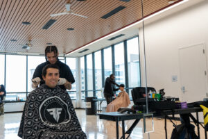 Male getting a haircut and smiling through a mirror.