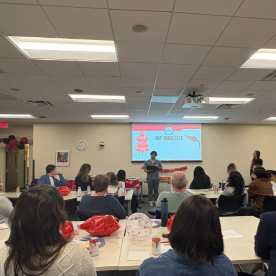A speaker addresses a full room of people at a graduation celebration