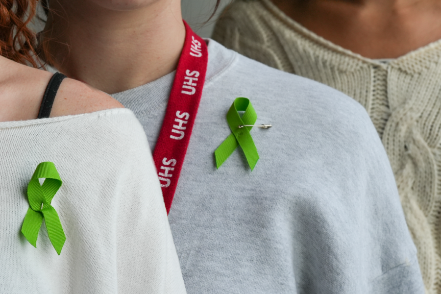 Three people wear green ribbons on their shirts