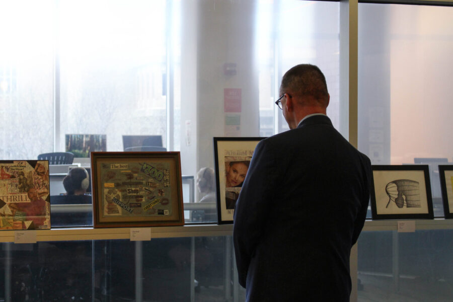 Person standing in front of art that is leaned against a window ledge.