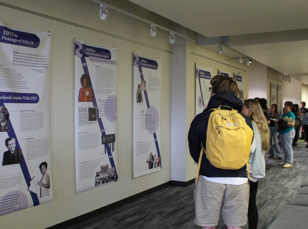 Students looking at vertical banners explaining the history of sexual assault activism.