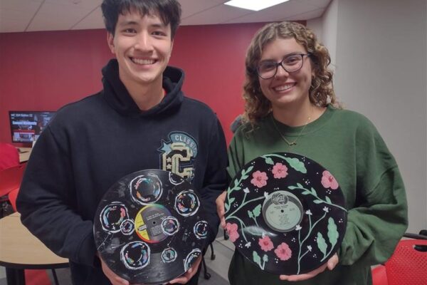 Two students posing with their painted vinyl records.