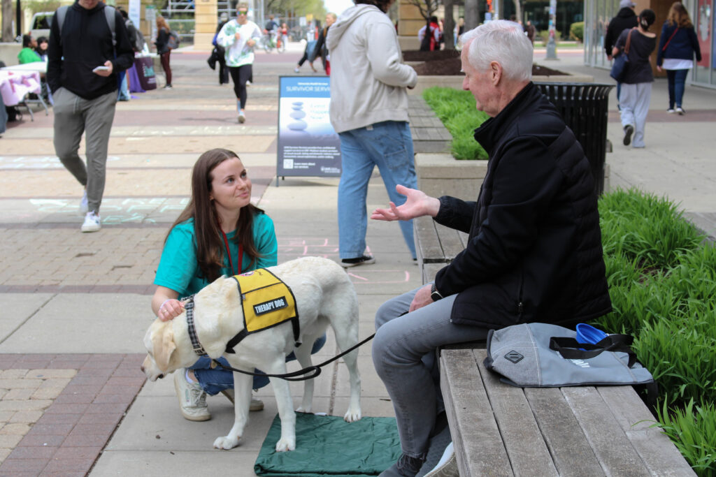 Student speaking with a service handler of a service dog while petting the dog.