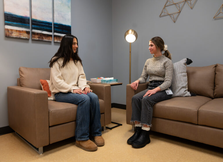 Survivor Services advocate, Rachel Parbs sitting with a student on a couch conversing.