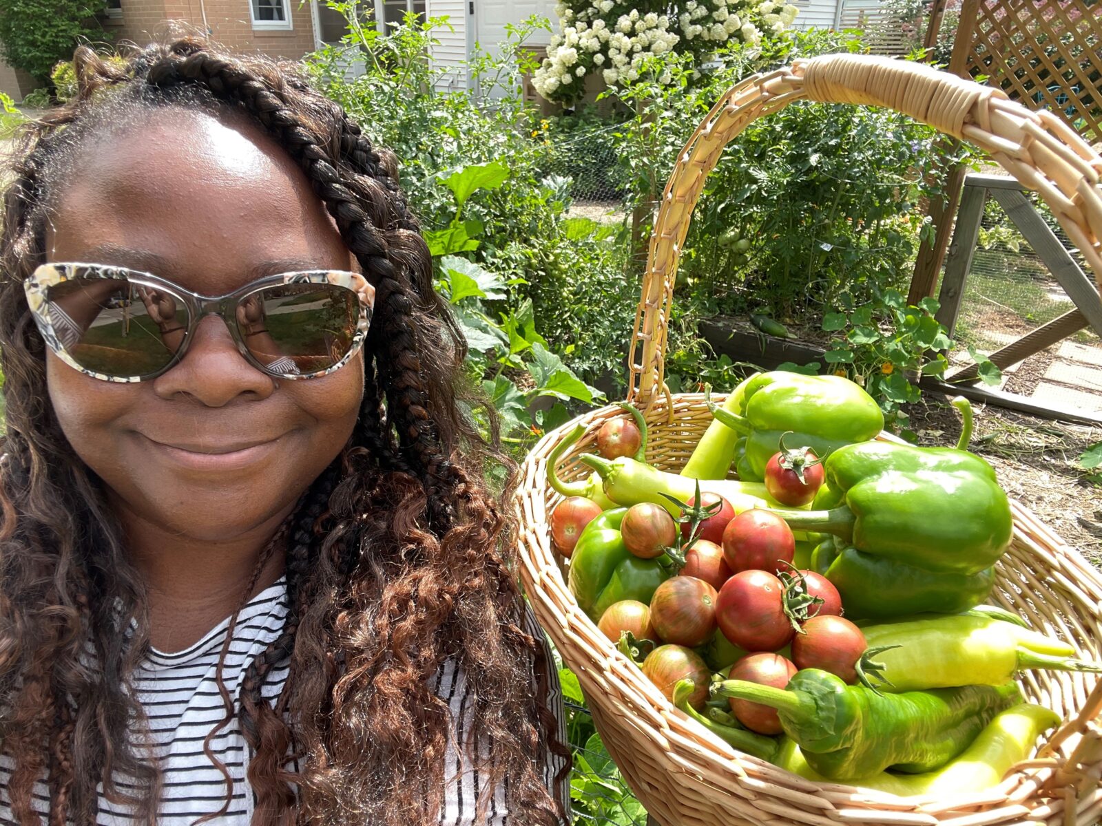 Danyelle posing with a basket of produce in her garden.