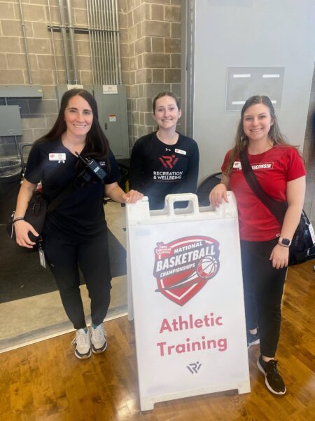 Erin Clark and colleagues pose next to Athletic Training sign