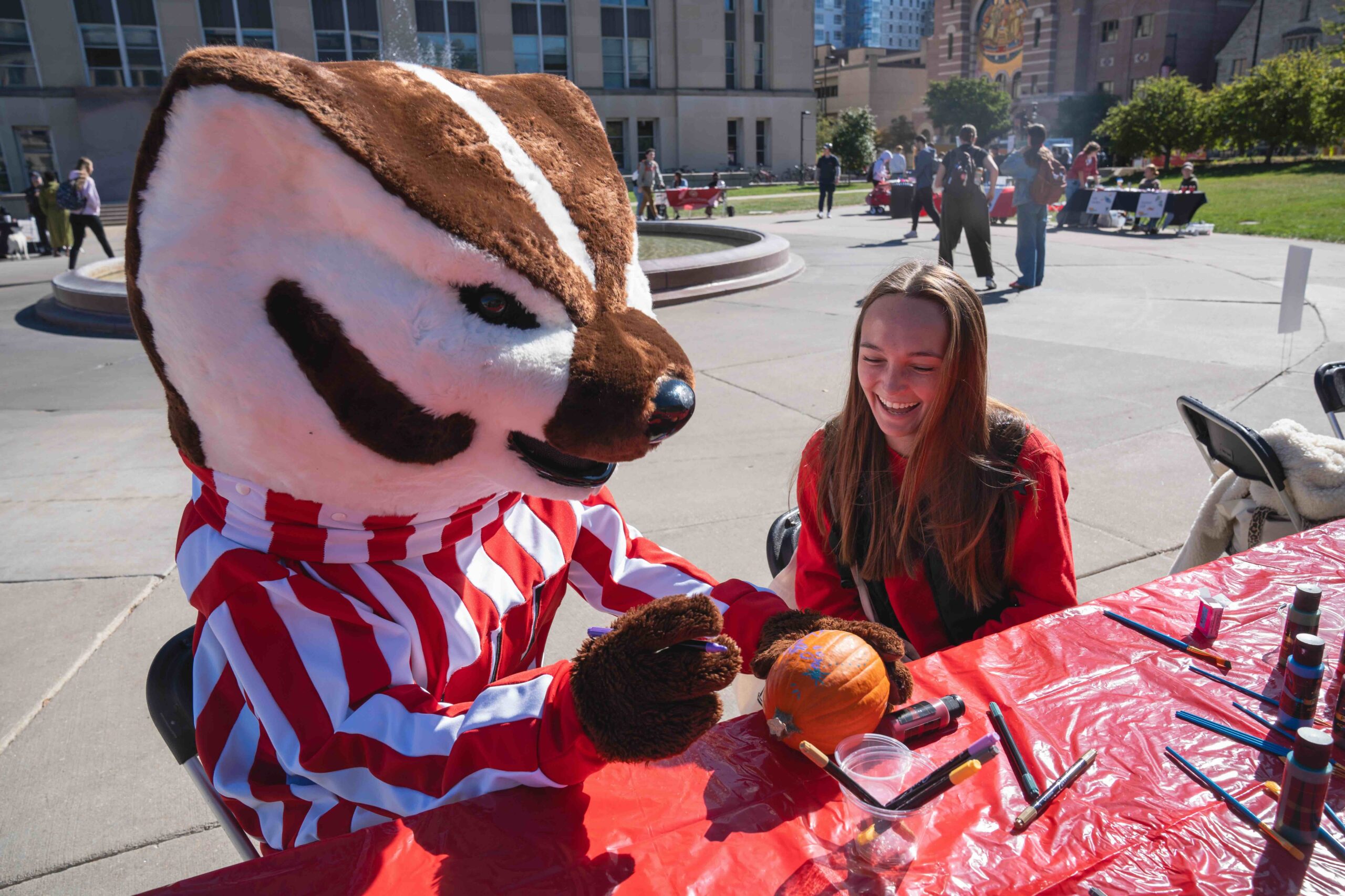 Bucky seated painting a pumpkin with a student at the mental wellbeing resource fair in 2025.