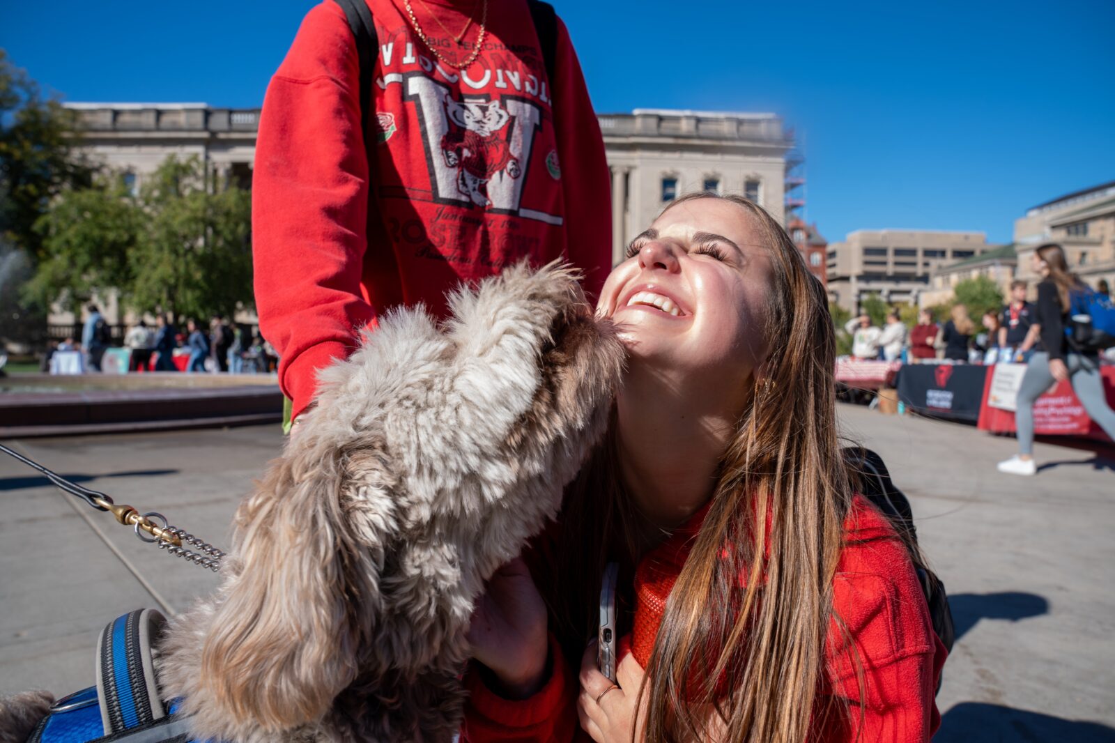 Student smiling as K9 Hoagie sniffs and licks her face at the Mental Wellbeing Resource Fair in 2025.