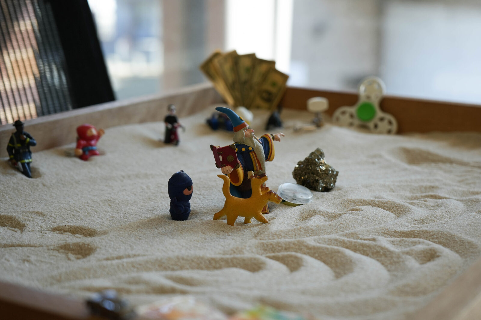 Mini figurines and objects placed in the sand.