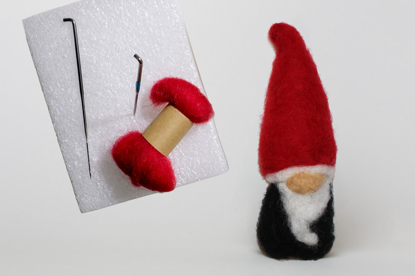 Needle-felted gnome next to felt and pin.