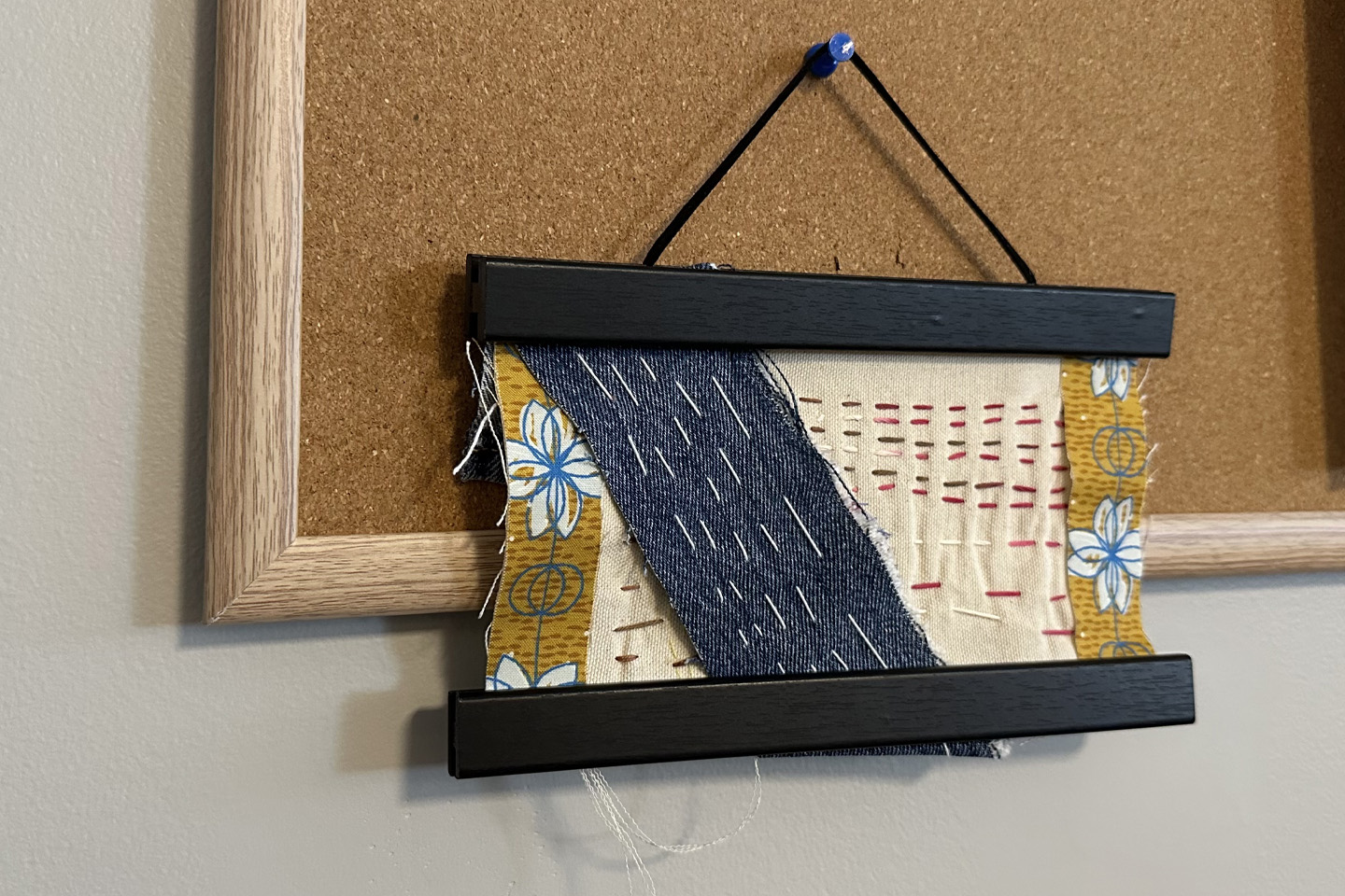 Hand stitching craft hung on corkboard.