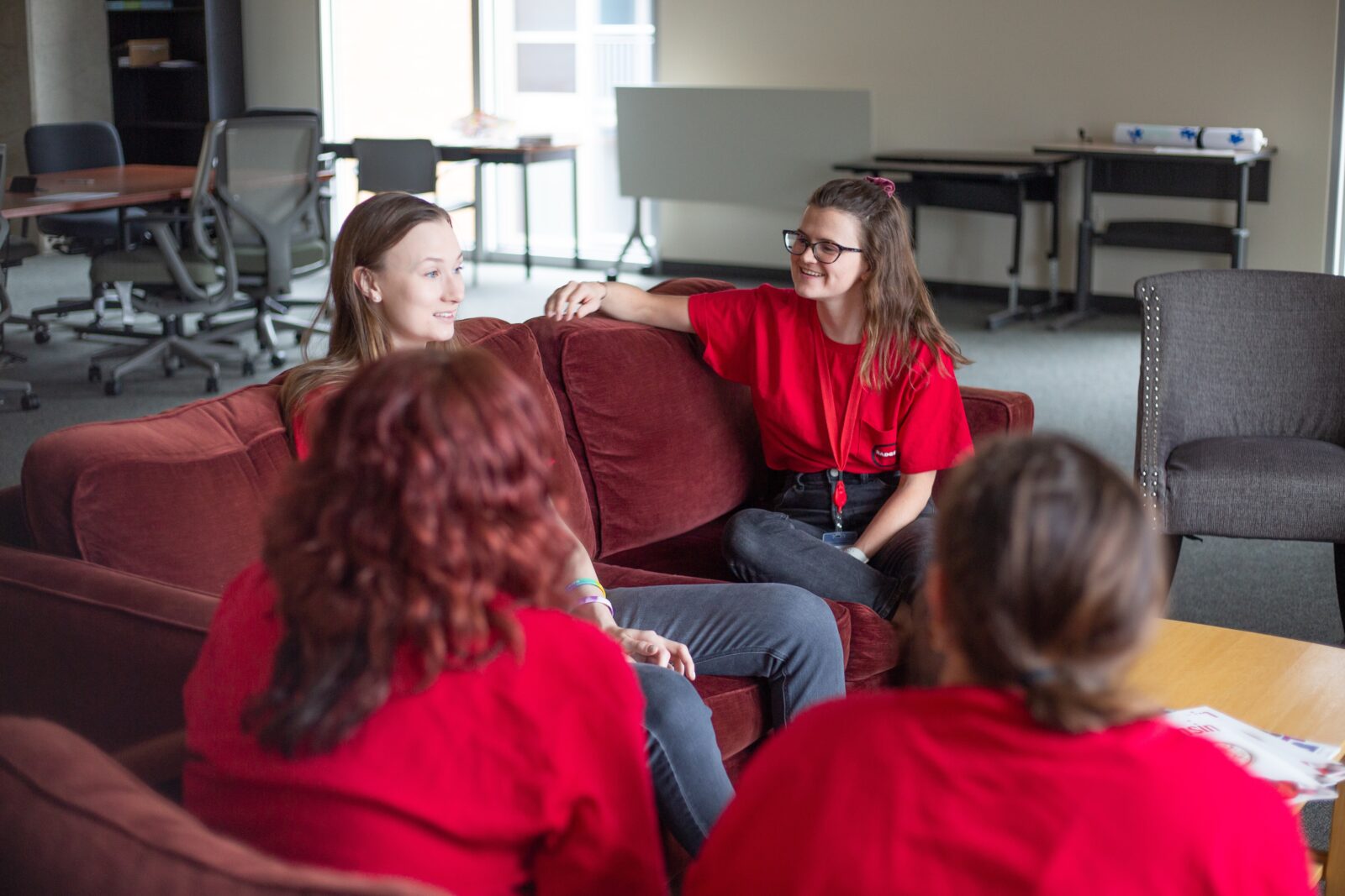 Students of badger recovery seated on a red couch speaking to each other.