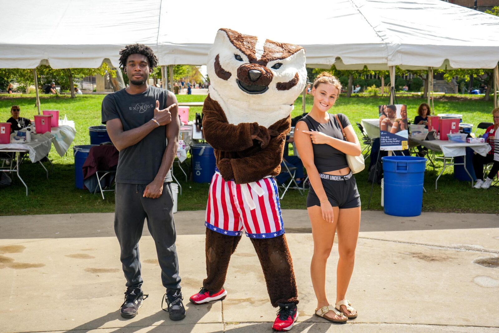 Students pose with Bucky and display bandaids on their shoulders at the Library Mall vaccine clinic in September 202